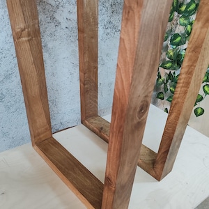 Puede incluir: Dos marcos de madera, cada uno con forma cuadrada, est&aacute;n unidos en la parte superior. Los marcos son de madera marr&oacute;n oscura con un patr&oacute;n de veta natural. Los marcos est&aacute;n sobre una superficie marr&oacute;n claro.