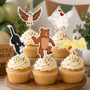 May include: Five cupcakes topped with animal-themed paper toppers. The toppers feature a black and white cat, a brown owl, a brown bear, a white chicken, and a yellow duck. Each cupcake has white frosting with small green and brown sprinkles.