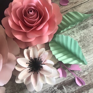 May include: A set of paper flowers in pink, white, and green. The flowers are layered and have a delicate, handmade look.