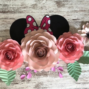 May include: A paper craft floral arrangement featuring pink and white paper flowers, green leaves, and a black and red Minnie Mouse ears headband.