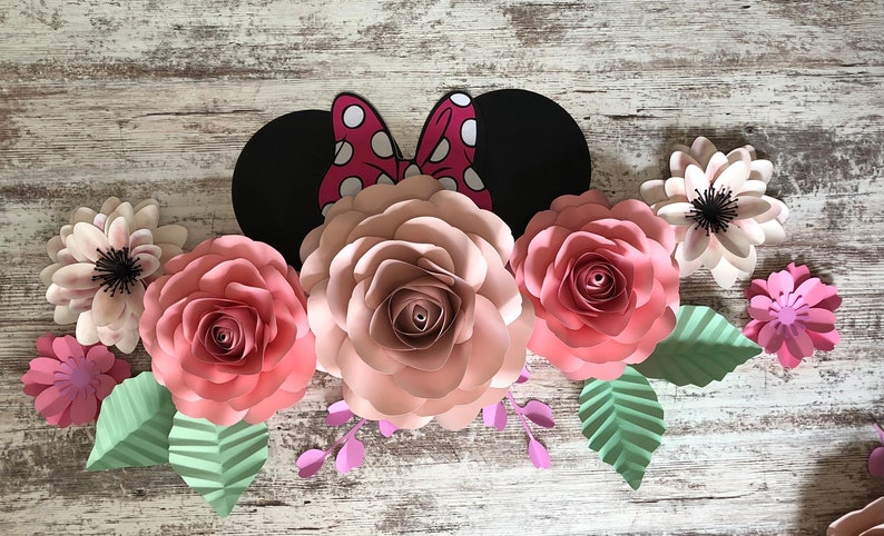 May include: A paper craft floral arrangement featuring pink and white paper flowers, green leaves, and a black and red Minnie Mouse ears headband.