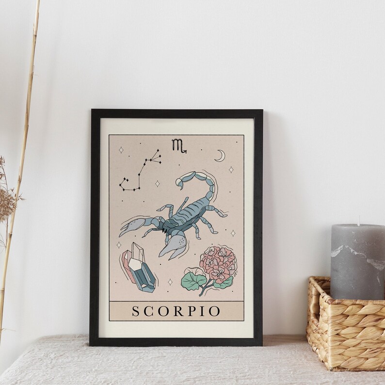 Pu&ograve; includere: Una stampa incorniciata nera con sfondo beige che presenta un'illustrazione di scorpione blu, una costellazione, un cristallo, un fiore e il testo "SCORPIO".