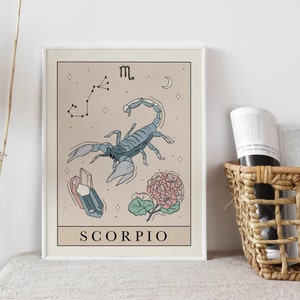 Pu&ograve; includere: Una stampa incorniciata beige e bianca con un'illustrazione di scorpione blu, una costellazione e un fiore rosa. Il testo "SCORPIO" &egrave; in fondo alla stampa.