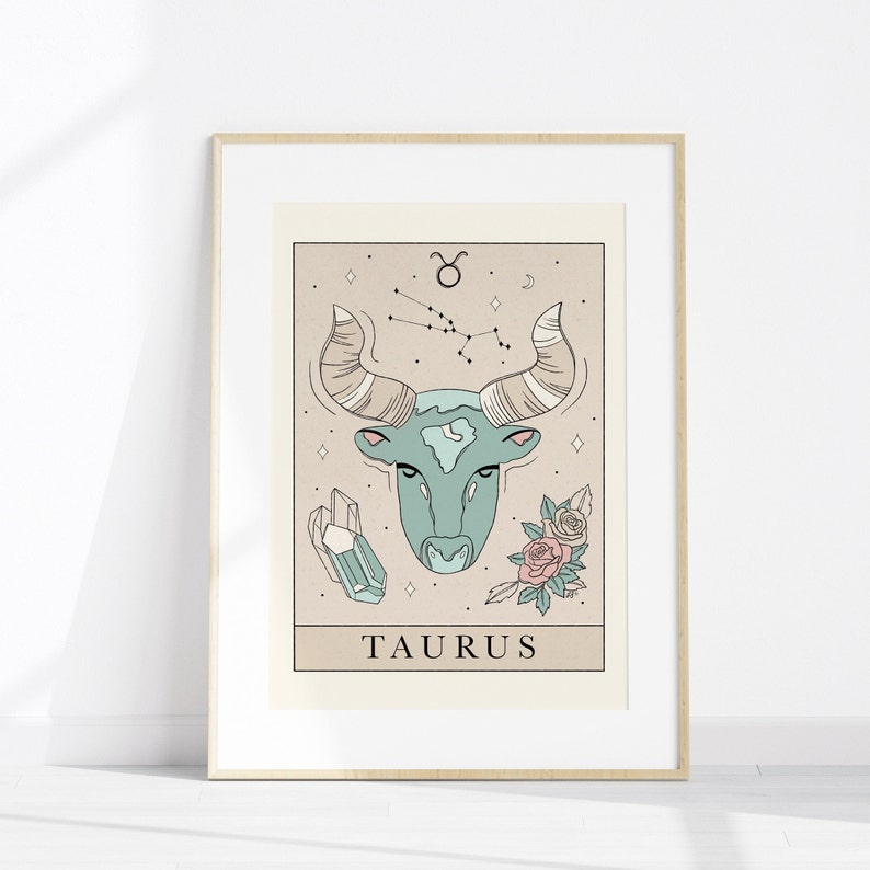 May include: A beige and brown illustrated print of the Taurus zodiac sign. The illustration features a blue bull's head with a constellation of stars above it. The print also includes a crystal and flowers.