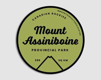May include: A green and black circular sticker with the text "Mount Assiniboine Provincial Park" and "#MountainCultureElevated" in a white circle. The sticker also includes the text "Canadian Rockies" and "390 sq km".