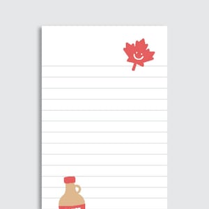 May include: A white rectangular notepad with horizontal black lines. The top right corner features a red maple leaf graphic with a smiling face. The bottom left corner displays a tan bottle graphic with a red cap and red base.