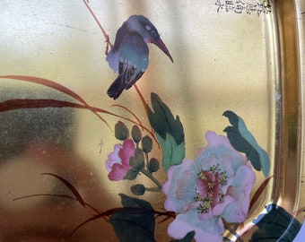 May include: A gold metal tray with a raised rope border. The tray features a painted design of a bird, flowers, and leaves. The tray has Chinese characters written on it.