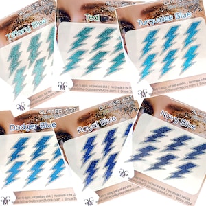 Peut inclure: Assortiment de tatouages ​​autocollants en paillettes dans différentes nuances de bleu, notamment Tiffany Blue, Teal, Turquoise Blue, Dodger Blue, Royal Blue et Navy Blue. Chaque feuille présente un motif d'éclair. Le texte "Glitter Stick On Tattoo" est imprimé sur chaque feuille.
