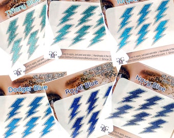 May include: Assortment of glitter stick-on tattoos in various shades of blue, including Tiffany Blue, Teal, Turquoise Blue, Dodger Blue, Royal Blue, and Navy Blue. Each sheet features a lightning bolt design. The text "Glitter Stick On Tattoo" is printed on each sheet.
