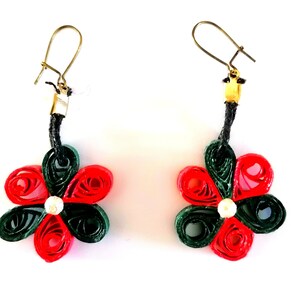 Pode incluir: Um par de brincos de flores de papel vermelho e verde com uma pérola branca no centro. Os brincos são presos a um cordão preto e ganchos dourados.