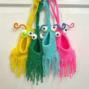 May include: Four crocheted hanging monster pouches in yellow, green, blue, and pink with googly eyes and pipe cleaner antennas.