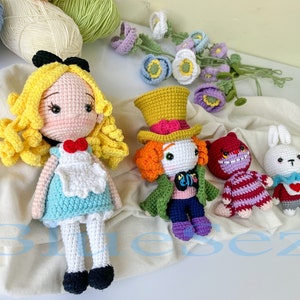 May include: Crocheted Alice in Wonderland characters, including Alice, the Mad Hatter, the Cheshire Cat, and the White Rabbit. The characters are all wearing colorful clothing and have detailed facial features.