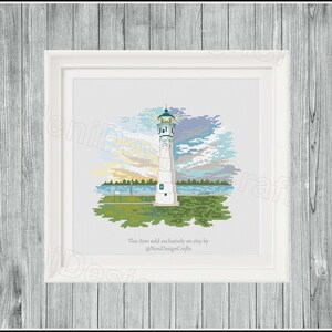 Peut inclure: Un motif de point de croix repr&eacute;sentant un phare blanc avec un toit vert et un ciel bleu avec des nuages. Le phare est situ&eacute; sur une petite &icirc;le avec de l'herbe verte et des arbres. Le texte "Marine City" est inscrit sur le phare. Cet article est vendu exclusivement sur Etsy par @NeniDesignCrafts.