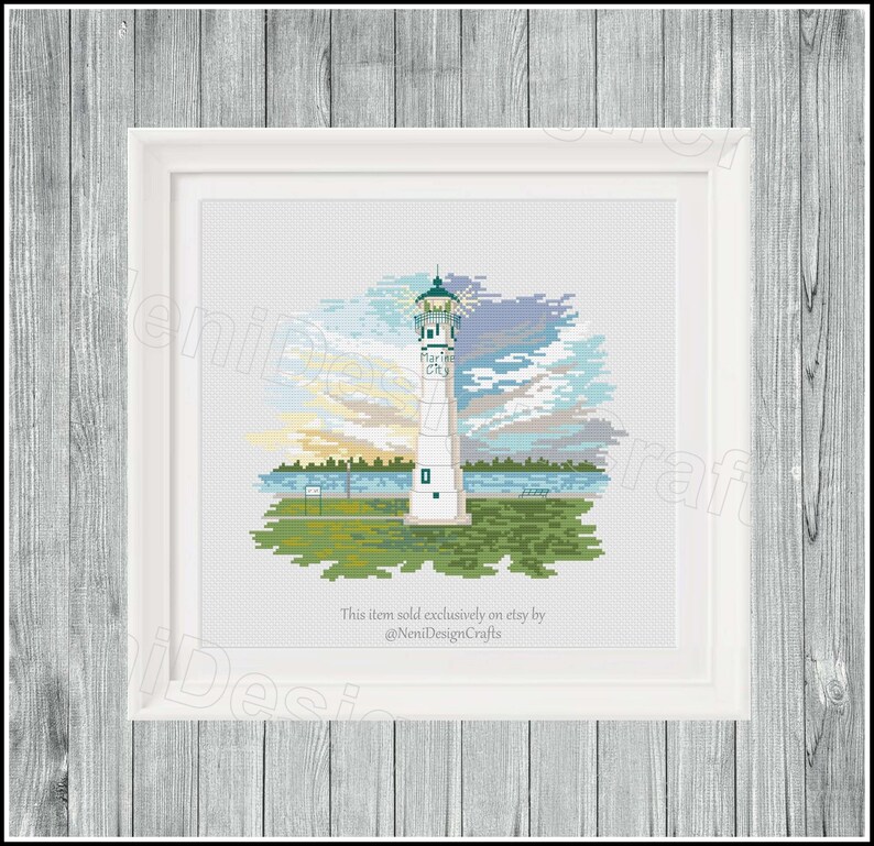 Peut inclure: Un motif de point de croix repr&eacute;sentant un phare blanc avec un toit vert et un ciel bleu avec des nuages. Le phare est situ&eacute; sur une petite &icirc;le avec de l'herbe verte et des arbres. Le texte "Marine City" est inscrit sur le phare. Cet article est vendu exclusivement sur Etsy par @NeniDesignCrafts.