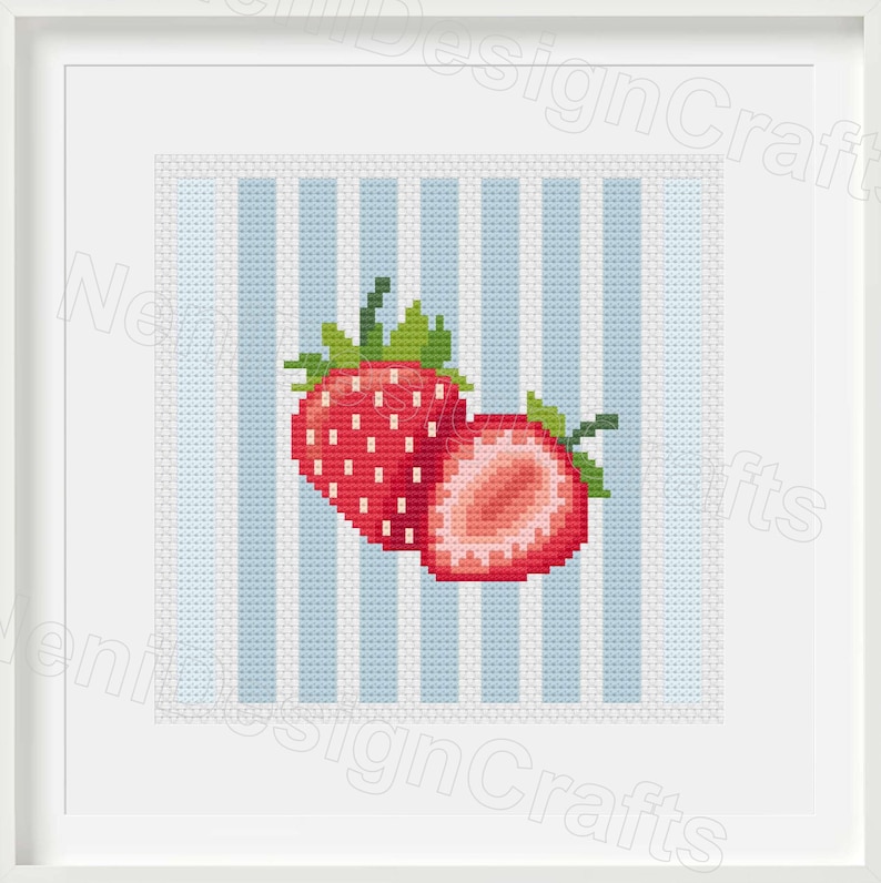 May include: Cross-stitch artwork featuring two red strawberries with green leaves, one whole and one sliced, set against a light blue and white striped background. The artwork is framed in a white square frame.
