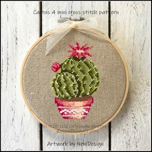 May include: A cross stitch pattern of a green cactus in a red and white pot with a pink flower on top. The pattern is framed in a wooden hoop and is on a white background. The text "Cactus 4 mini cross stitch pattern" is at the top of the image.