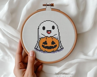 May include: A cross-stitch design featuring a smiling ghost and a pumpkin, set within an embroidery hoop. The text "Happy Ghost - cross stitch pattern" is at the top. The text "Mini PDF pattern 7.8 x 9.1 cm" is at the bottom.