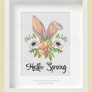 Puede incluir: Patrón de punto de cruz con un conejo con detalles florales. Las orejas del conejo son de tela rosa y marrón, y las flores son blancas, rosas y verdes. El texto "Hello Spring" está escrito en letras cursivas negras debajo del conejo.
