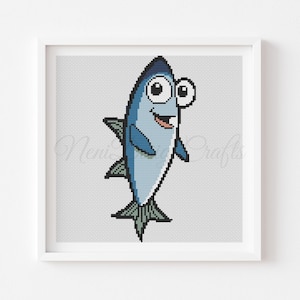 May include: A framed cross-stitch of a cartoon fish. The fish is primarily light blue with darker blue accents on its fins and tail. It has large, expressive eyes and a smiling mouth. The background is a light gray, cross-stitch pattern.