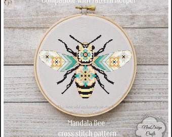May include: A cross stitch pattern of a bee with a mandala design. The bee is yellow and black with teal and white wings. The pattern is compatible with Pattern Keeper. "Mandala Bee - cross stitch pattern" is written below the bee.