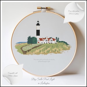 May include: Cross stitch pattern of the Big Sable Point Light in Ludington, Michigan. The lighthouse is white with a black stripe and is surrounded by green trees and sand dunes. The pattern is available as a PDF download.
