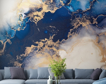 May include: A living room interior with a blue sectional sofa, a coffee table, and a blue beanbag chair. The wall behind the sofa is decorated with a large abstract painting featuring blue, white, and gold colors.