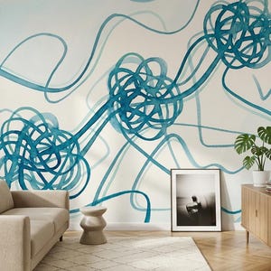 May include: A modern living room with a beige sofa, wooden cabinet, and a framed black and white photograph. The wall features a large abstract watercolor mural in shades of teal and blue. A small side table and a potted plant complete the scene.