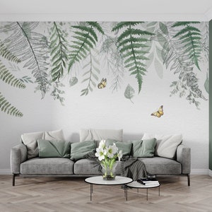 May include: A living room interior with a gray sofa and a white wall with a green and gray fern and butterfly wallpaper design.