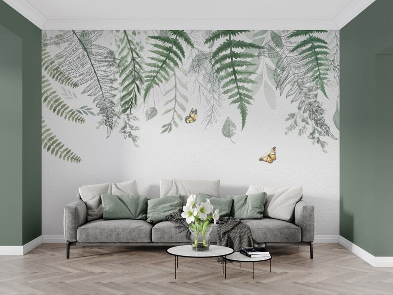 May include: A living room interior with a gray sofa and a white wall with a green and gray fern and butterfly wallpaper design.