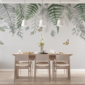 May include: A dining room with a white wall featuring a watercolor mural of green ferns and butterflies. The room has a wooden table with six chairs.