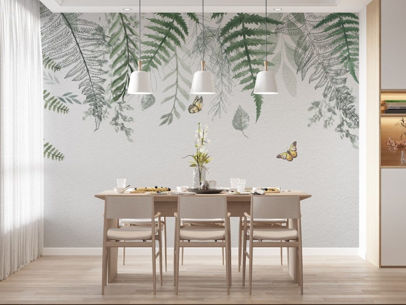 May include: A dining room with a white wall featuring a watercolor mural of green ferns and butterflies. The room has a wooden table with six chairs.