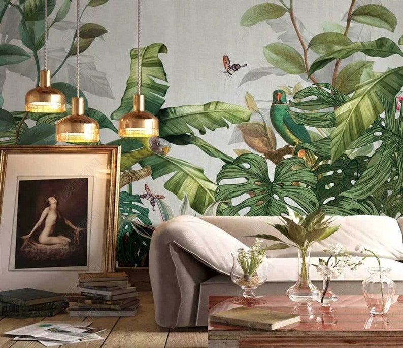 Puede incluir: Un sof&aacute; blanco con tres l&aacute;mparas colgantes doradas sobre &eacute;l. La pared detr&aacute;s del sof&aacute; est&aacute; cubierta con un papel tapiz tropical con hojas verdes, un loro y mariposas.