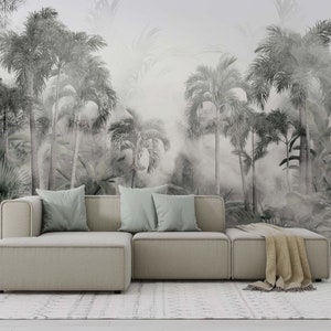 May include: A modern sectional sofa with light gray upholstery and light blue throw pillows. The sofa sits in front of a black and white mural of a tropical forest with palm trees. A beige throw blanket rests on the ottoman.