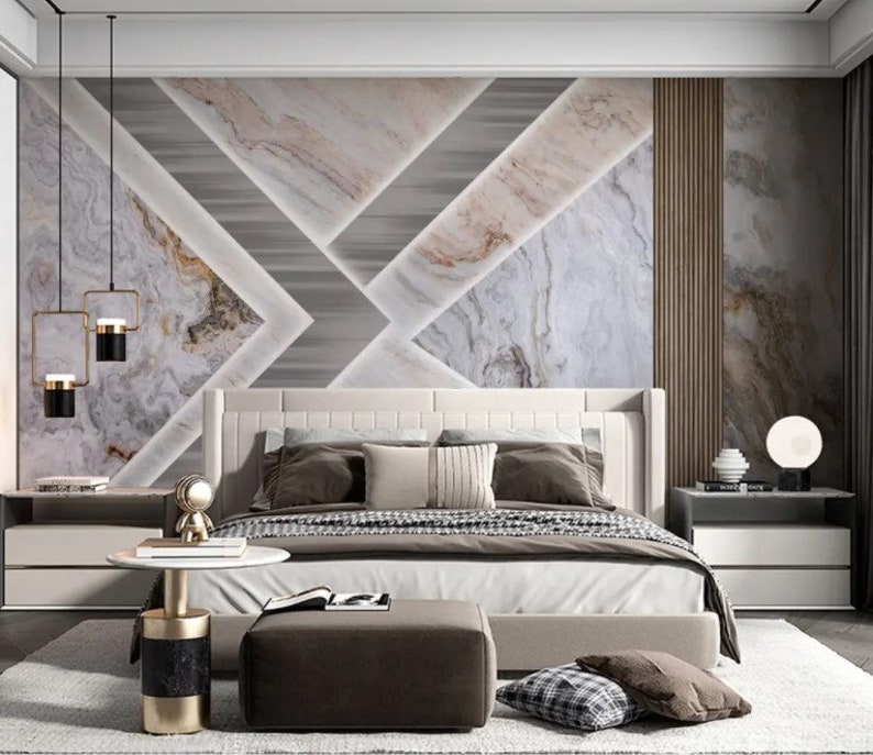 Puede incluir: Un dormitorio con una cama con estructura blanca y un papel tapiz con estampado geom&eacute;trico que presenta un dise&ntilde;o de m&aacute;rmol. La cama tiene un edred&oacute;n blanco y almohadas marrones. Hay dos mesitas de noche con l&aacute;mparas y una peque&ntilde;a mesa redonda con base dorada.
