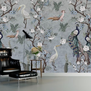 May include: A living room with a gray wall featuring a floral wallpaper with peacocks and white birds. A black leather armchair and ottoman are in the foreground.