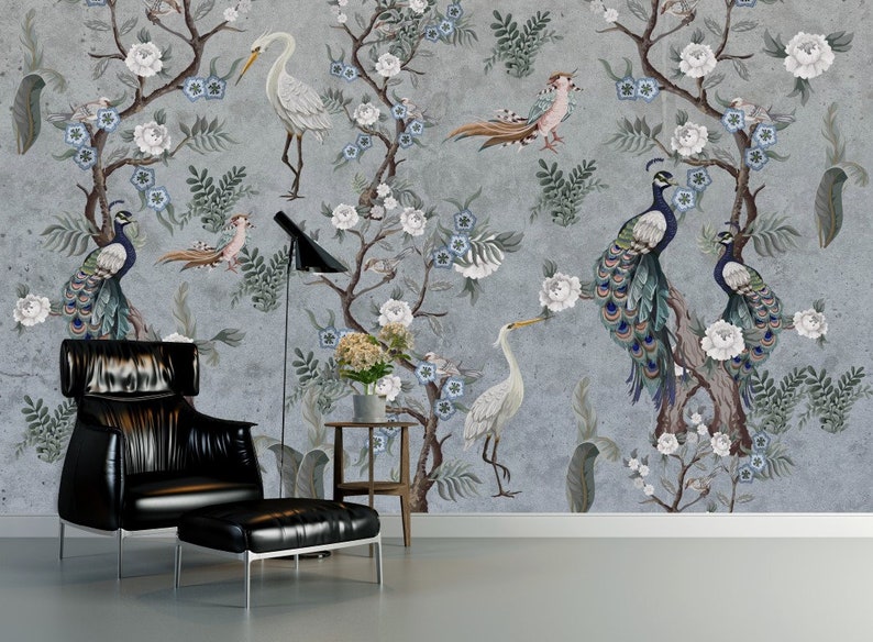 May include: A living room with a gray wall featuring a floral wallpaper with peacocks and white birds. A black leather armchair and ottoman are in the foreground.
