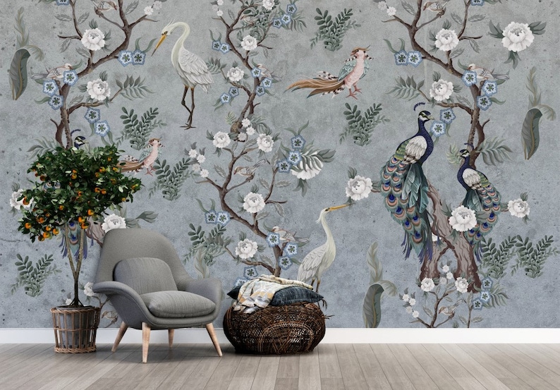 May include: A gray wall mural with a floral design featuring white flowers, blue flowers, and green leaves. There are peacocks, a heron, and other birds in the design. The mural is in a room with a gray armchair and a woven basket.