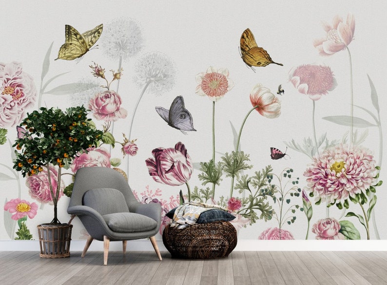 May include: A floral wallpaper mural with a gray armchair and a woven ottoman in front of it. The wallpaper features pink, white, and green flowers, as well as butterflies.