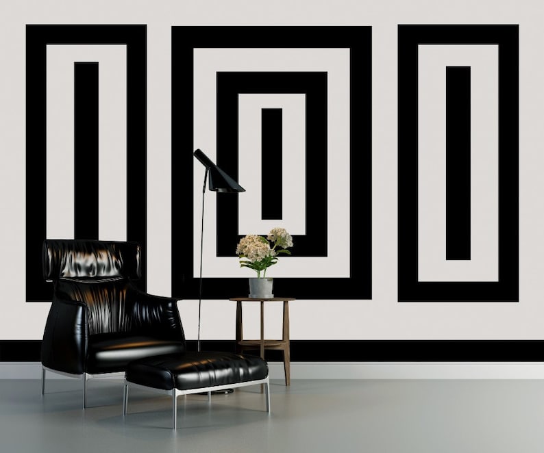 Puede incluir: Un sill&oacute;n de cuero negro con un reposapi&eacute;s a juego se encuentra frente a una pared blanca con un patr&oacute;n geom&eacute;trico en blanco y negro. Una peque&ntilde;a mesa auxiliar de madera con una planta en maceta se encuentra junto al sill&oacute;n.