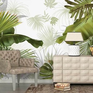 May include: A beige armchair with a tufted back and a white lamp on a beige dresser with a tropical leaf patterned wallpaper in the background.