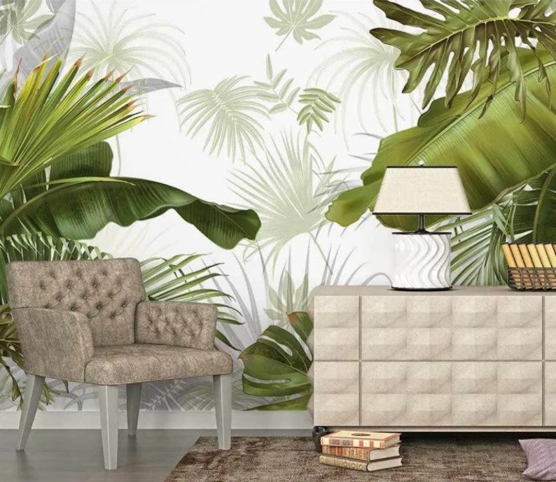 May include: A beige armchair with a tufted back and a white lamp on a beige dresser with a tropical leaf patterned wallpaper in the background.
