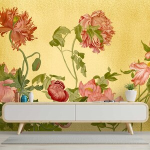 May include: A floral wallpaper mural with a gold background featuring pink and red flowers with green leaves. The wallpaper is displayed in a living room setting with a white console table and two side tables.