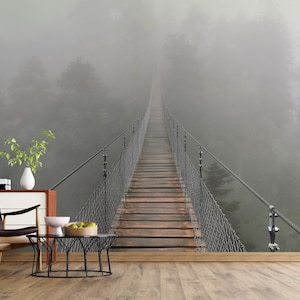 May include: A wooden suspension bridge stretches into the distance, disappearing into a thick fog. The bridge is surrounded by trees and the fog creates a mysterious and atmospheric scene.