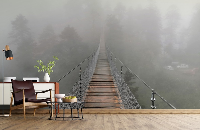 May include: A wooden suspension bridge stretches into the distance, disappearing into a thick fog. The bridge is surrounded by trees and the fog creates a mysterious and atmospheric scene.