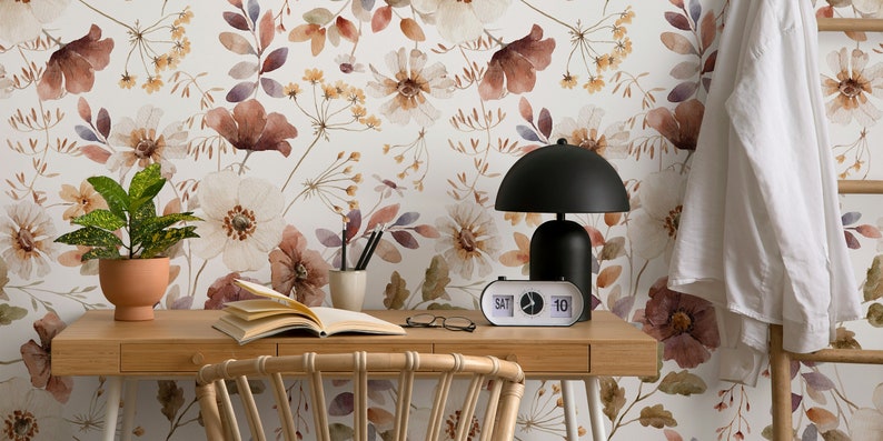 Puede incluir: Un escritorio de oficina en casa con un papel tapiz floral con flores de acuarela en tonos marrones, blancos y amarillos. El escritorio tiene una tapa de madera y una l&aacute;mpara negra con un reloj blanco que marca "S&Aacute;B 10".