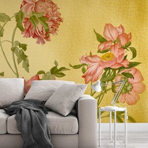 May include: A white sofa with a grey throw blanket in front of a wall with a floral pattern. The floral pattern features pink peonies on a yellow background.