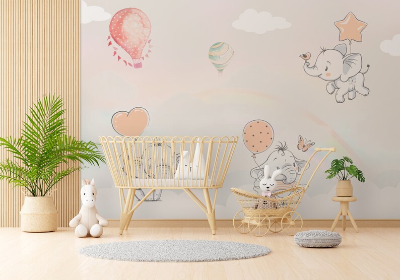 May include: A nursery room with a white crib, a wicker stroller with a stuffed bunny, and a white stuffed unicorn. The walls are decorated with a pink and white watercolor mural of elephants, butterflies, and hot air balloons.