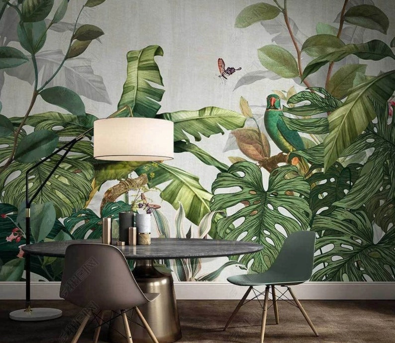 Puede incluir: Un comedor con un papel tapiz tropical con grandes hojas verdes, una l&aacute;mpara blanca, una mesa de madera oscura y dos sillas. El papel tapiz tiene un loro verde y una mariposa.