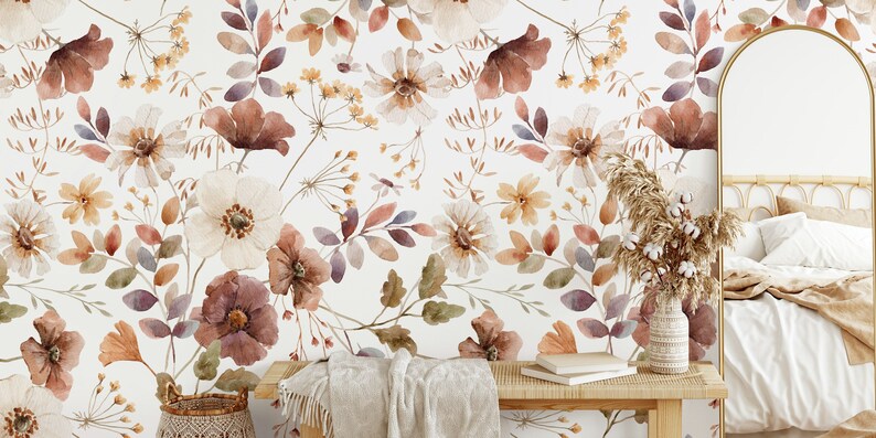 Puede incluir: Un papel tapiz floral de acuarela con fondo blanco y un patr&oacute;n de flores y hojas marrones, naranjas y moradas. El papel tapiz se muestra en un ambiente de dormitorio con una cama, un espejo y una mesita de noche.