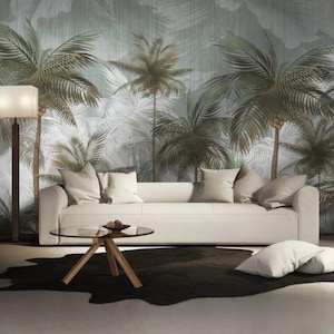 May include: A white sofa with pillows sits in front of a wall with a tropical palm tree wallpaper. A glass coffee table sits in front of the sofa. A black and white cowhide rug is on the floor.
